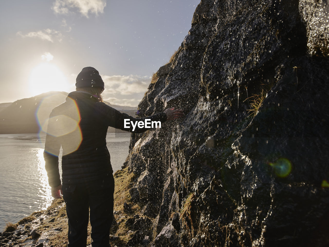 Woman touching water streaming over rocks in the faroe islands