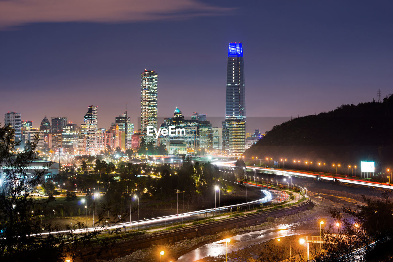 HIGH ANGLE VIEW OF ILLUMINATED CITY AGAINST SKY AT NIGHT