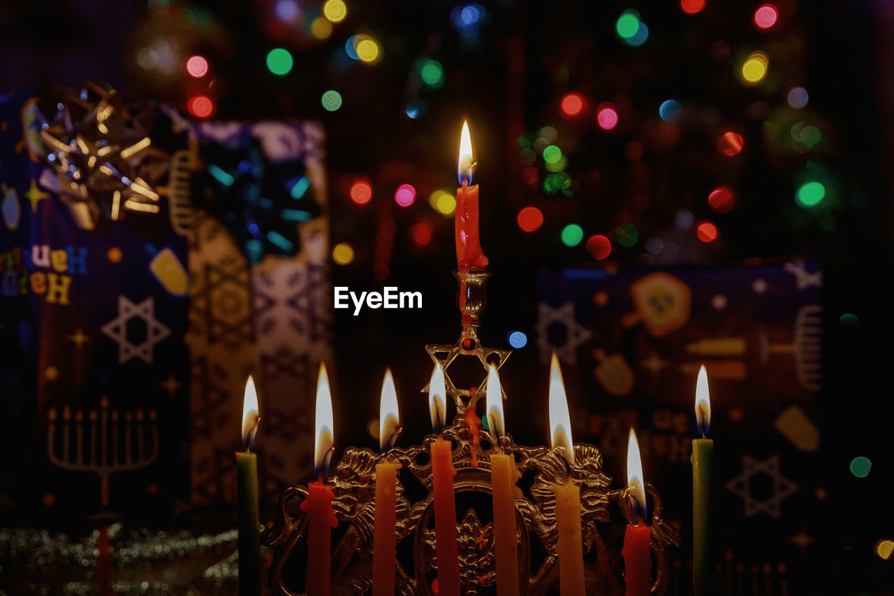 Close-up of illuminated candles against lighting equipment