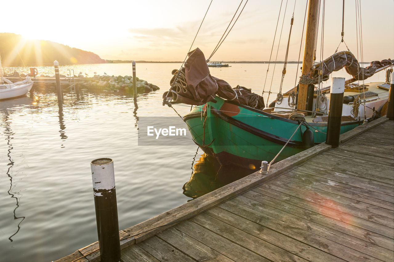 FISHING BOATS MOORED ON PIER AGAINST SKY