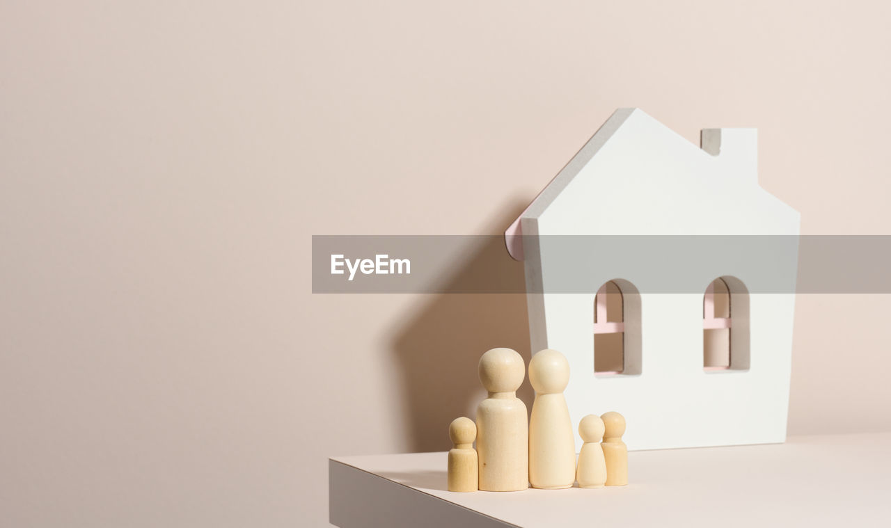 Wooden family figurines, model house on a beige background. real estate purchase, rental concept. m