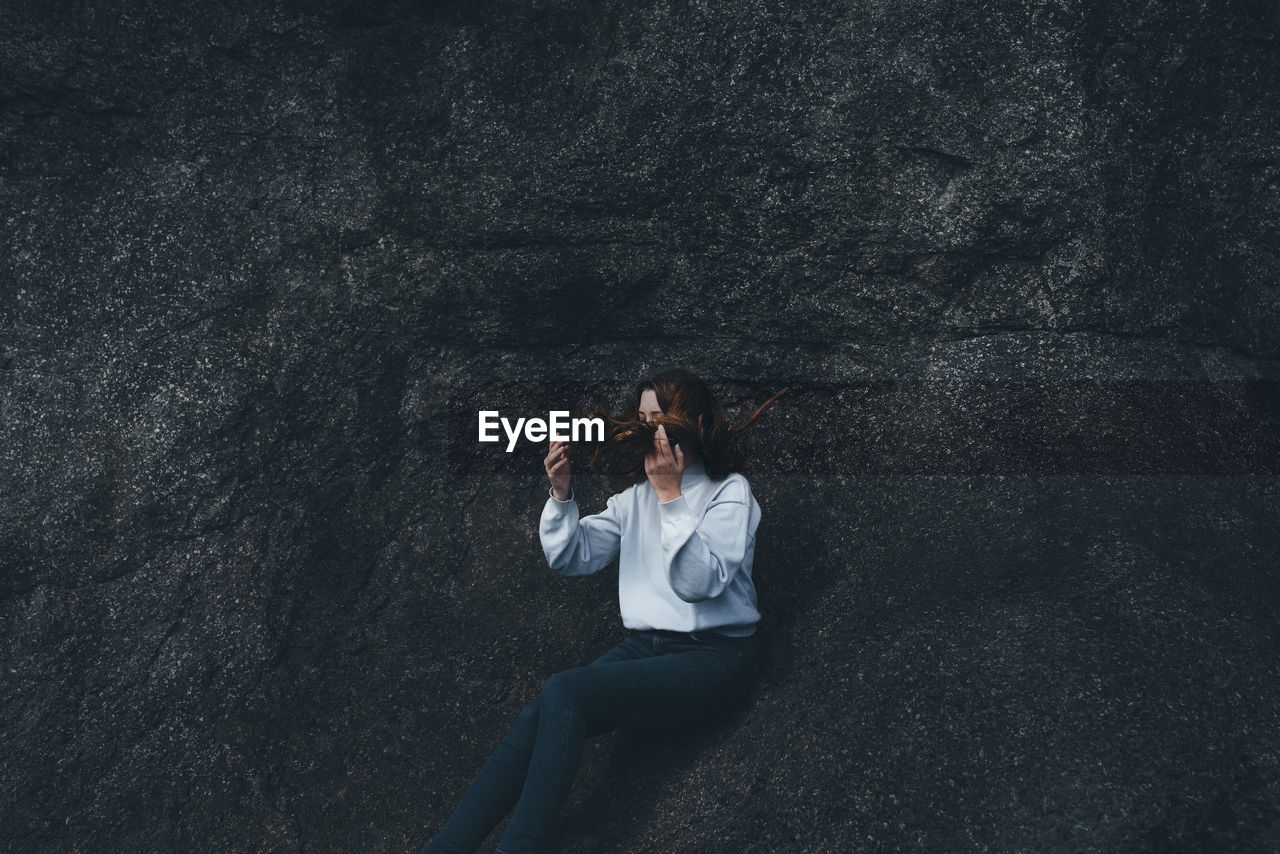 Young woman sitting on rock formation