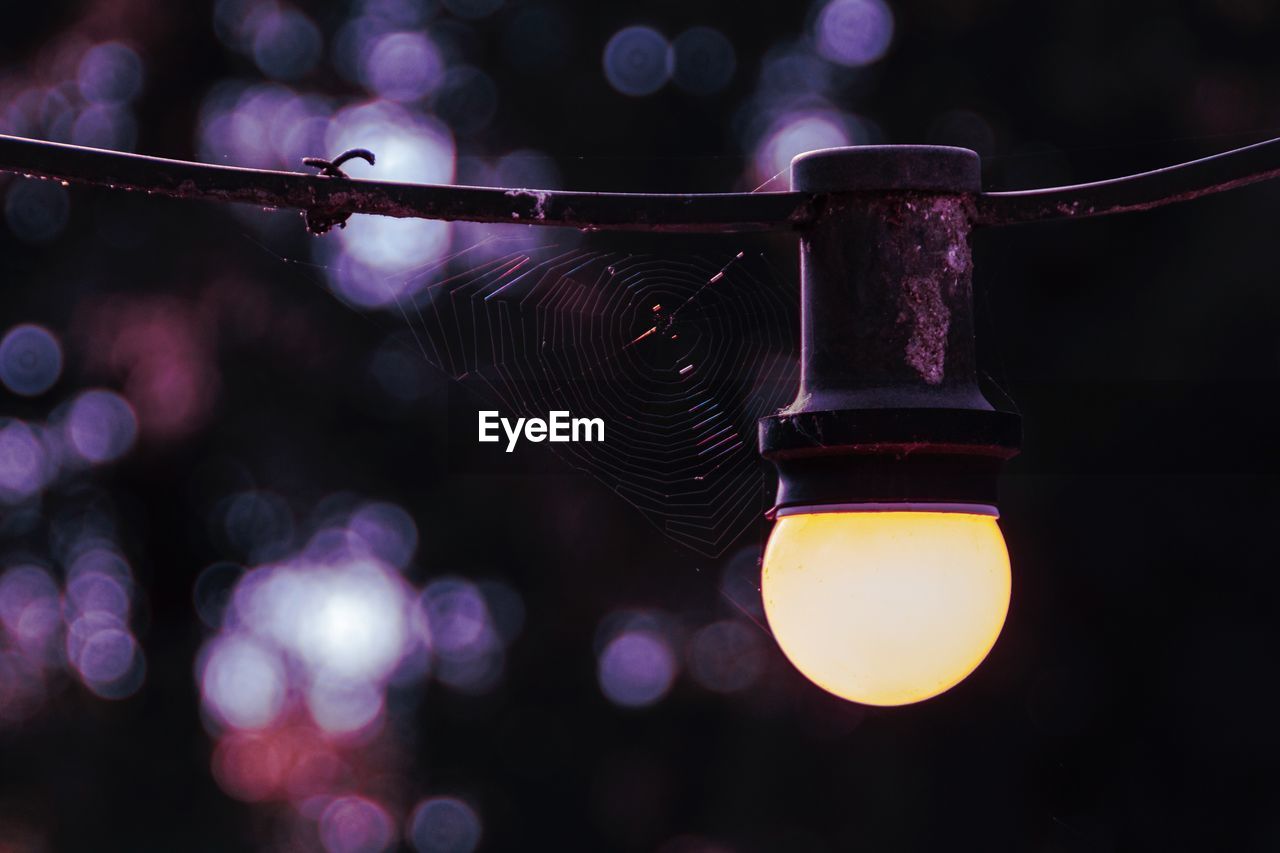 Low angle view of illuminated lighting equipment hanging at night