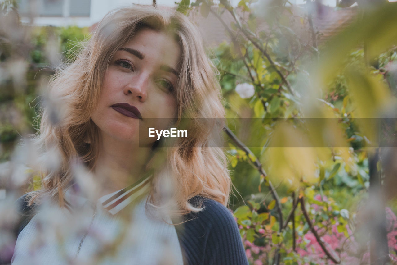 Young woman looking away by plants