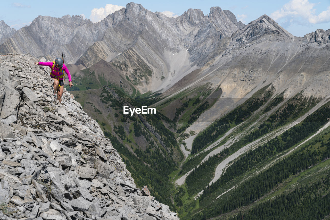 Female hiker scrambling along high ridge in kananaskis alberta