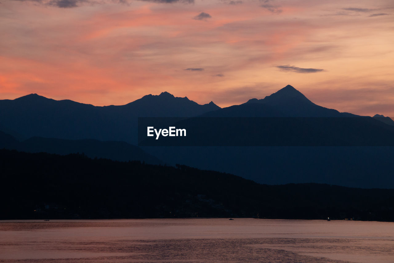 Scenic view of silhouette mountains against orange sky