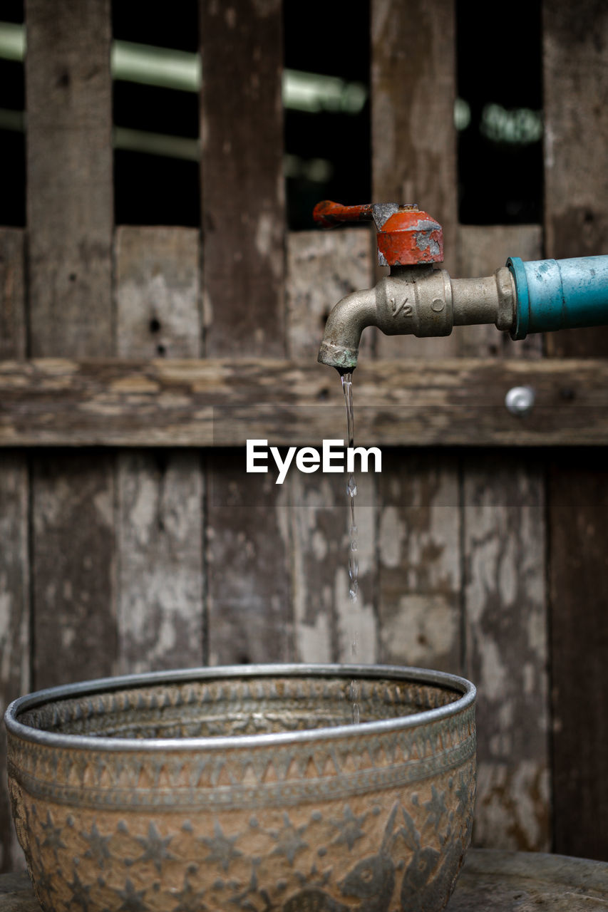 CLOSE-UP OF FAUCET AGAINST WALL IN WATER