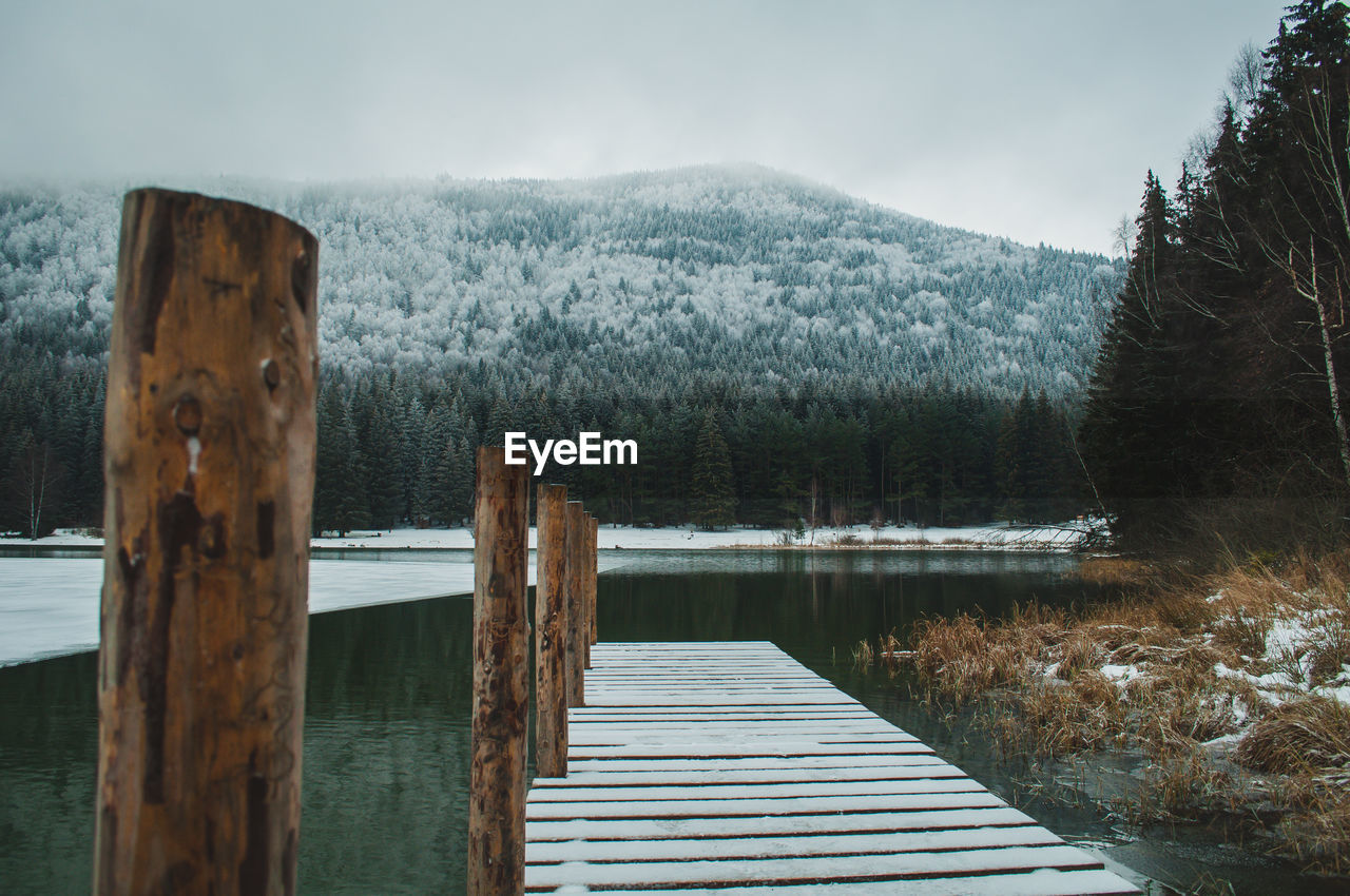 Pier over lake against sky during winter