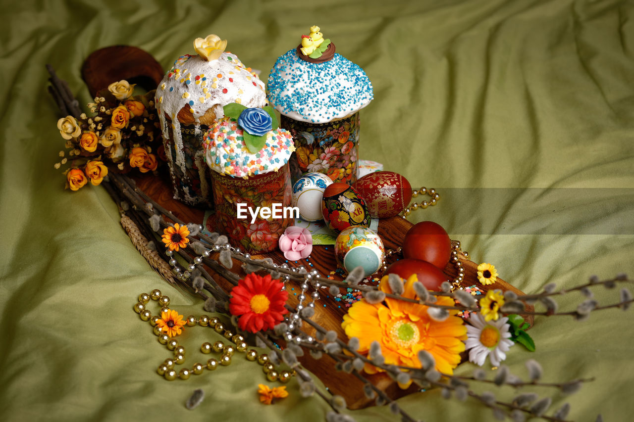 High angle view of decorations and colorful easter eggs on textile