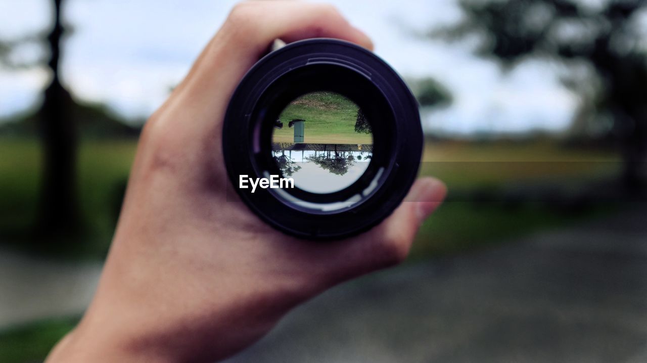 Cropped hand holding camera lens