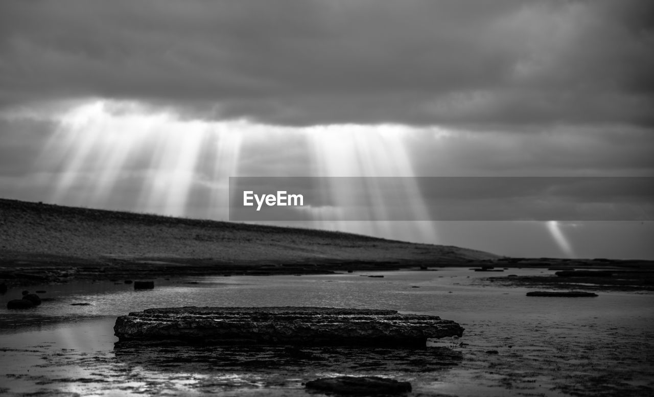 Sunlight streaming through storm clouds over sea