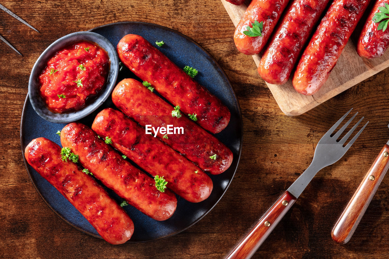 Cooked sausages with ketchup, shot from the top on a dark rustic wooden table. delicious barbecue