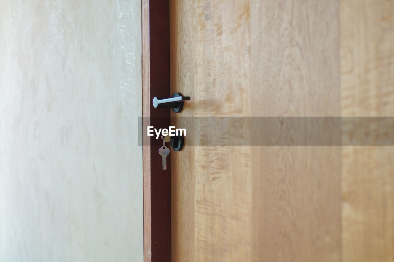 Selective focus on modern style of knob on wooden door with keys hanging on lock