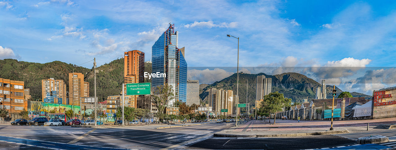 Panoramic view of street by buildings in city against sky