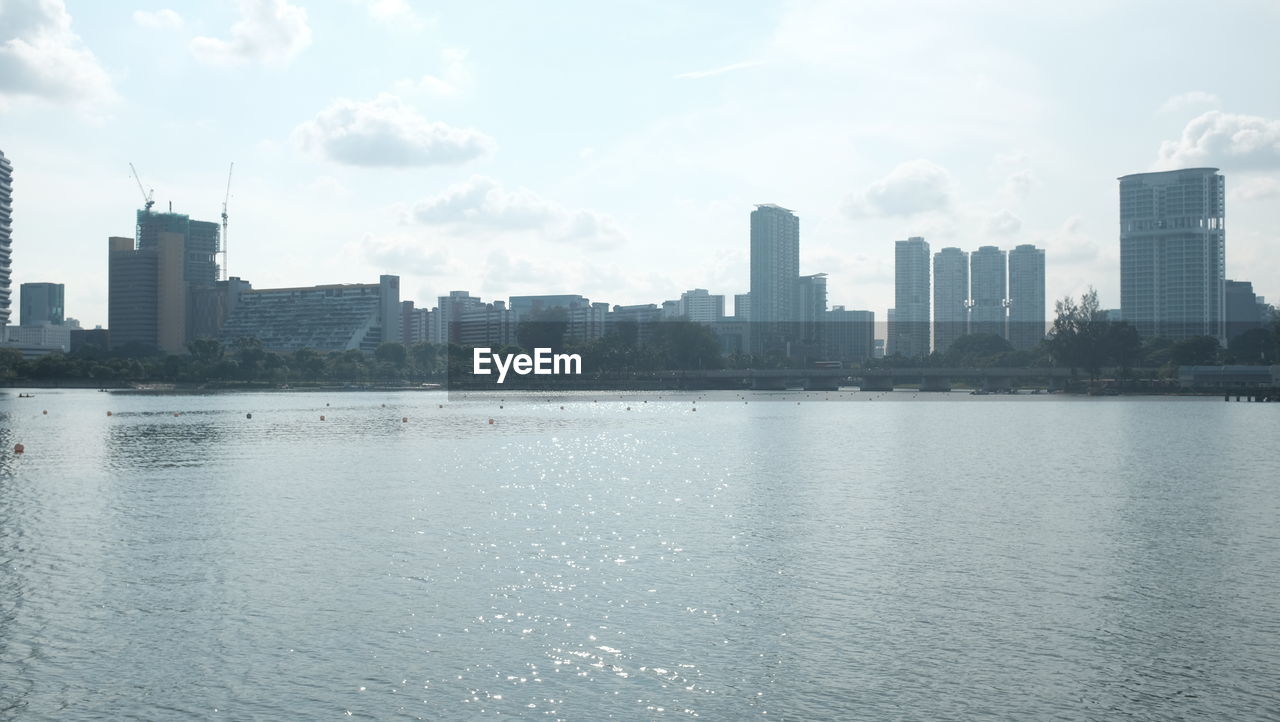 Scenic view of river by buildings against sky