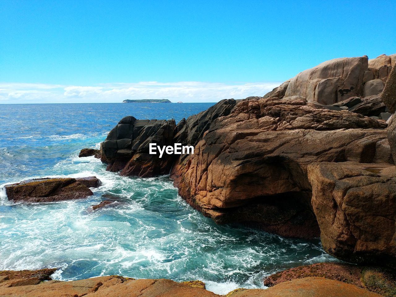 Rock formations by sea against clear blue sky