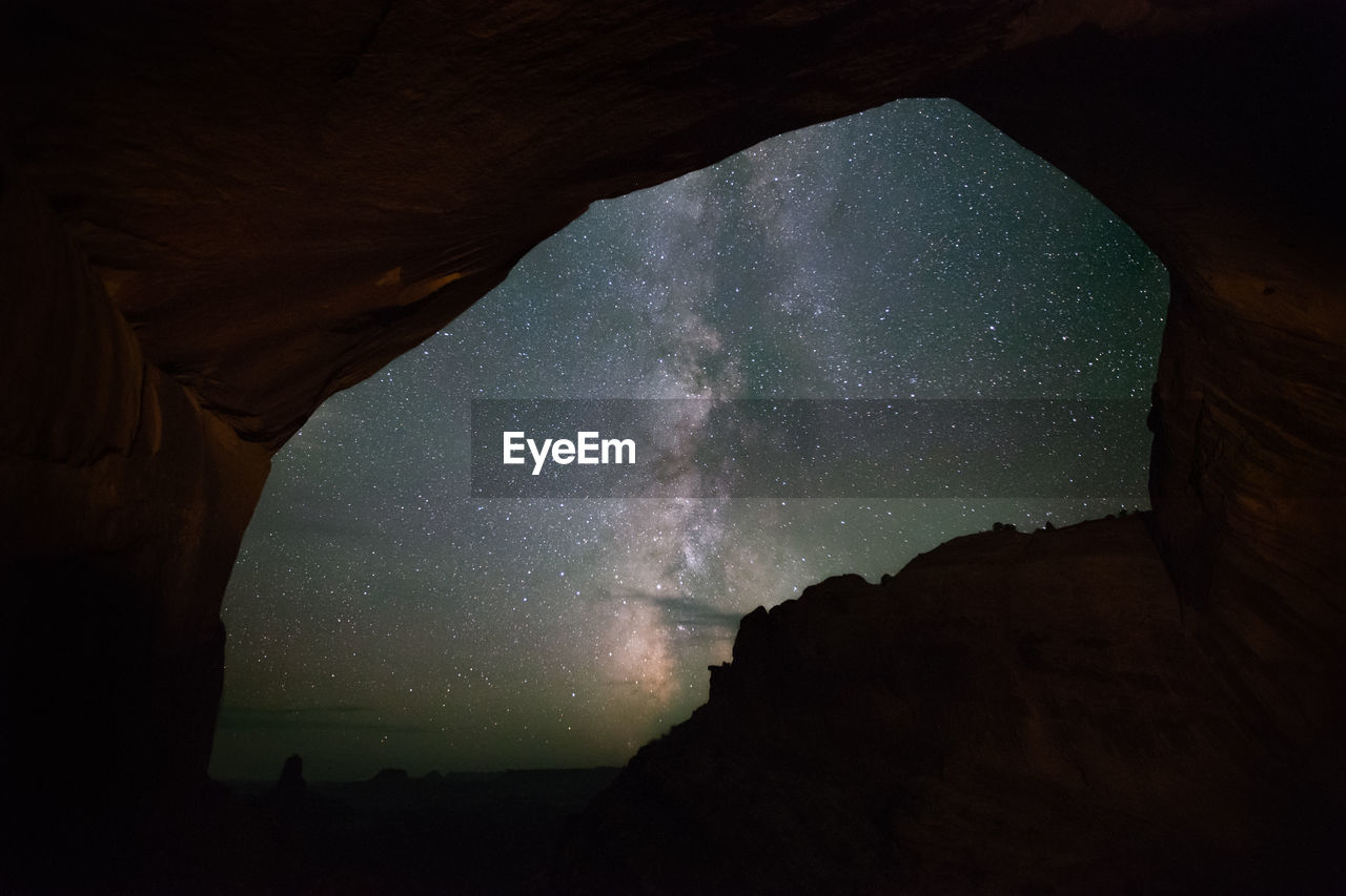 Low angle view of starry field seen through rock formation