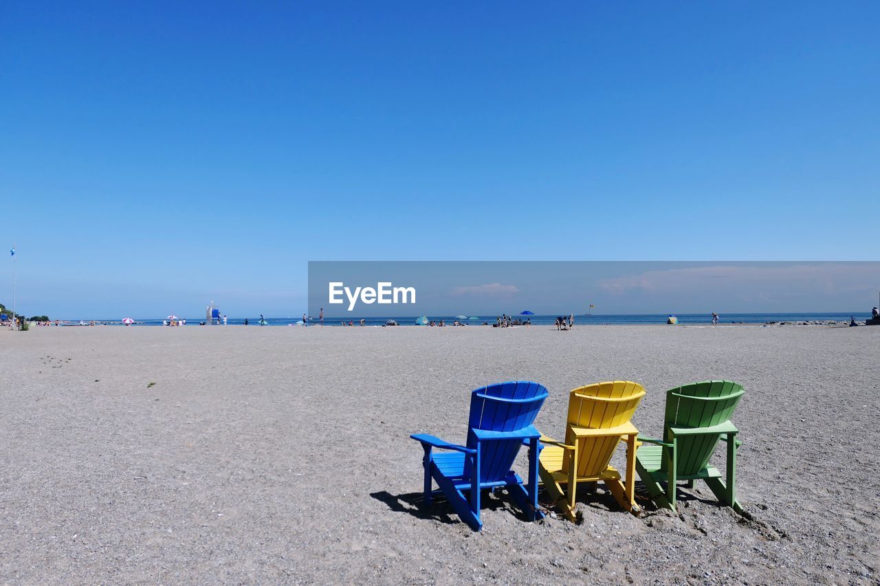 Chairs on beach against clear blue sky