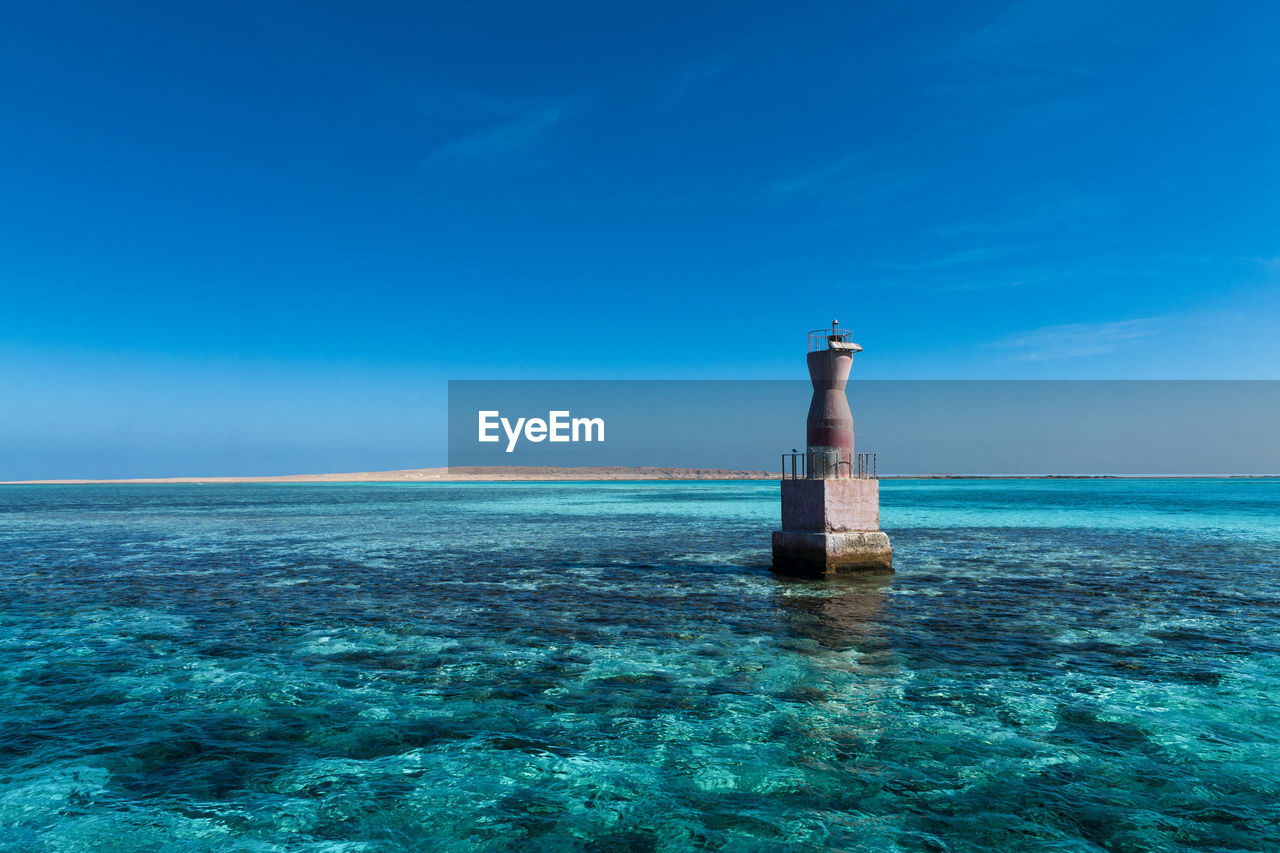 Lighthouse by sea against sky