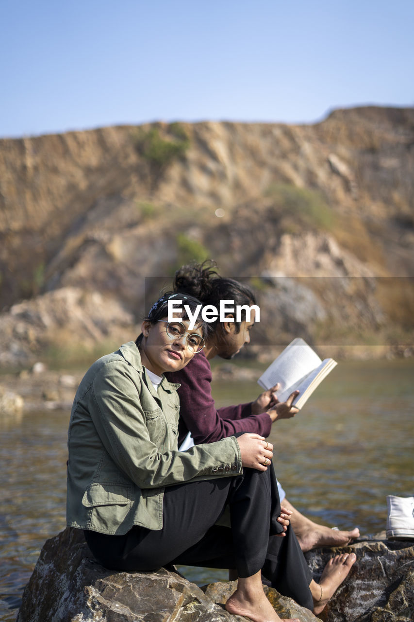 An indian couple sitting beside a lake having a romantic time. guy reading a book near the lake.