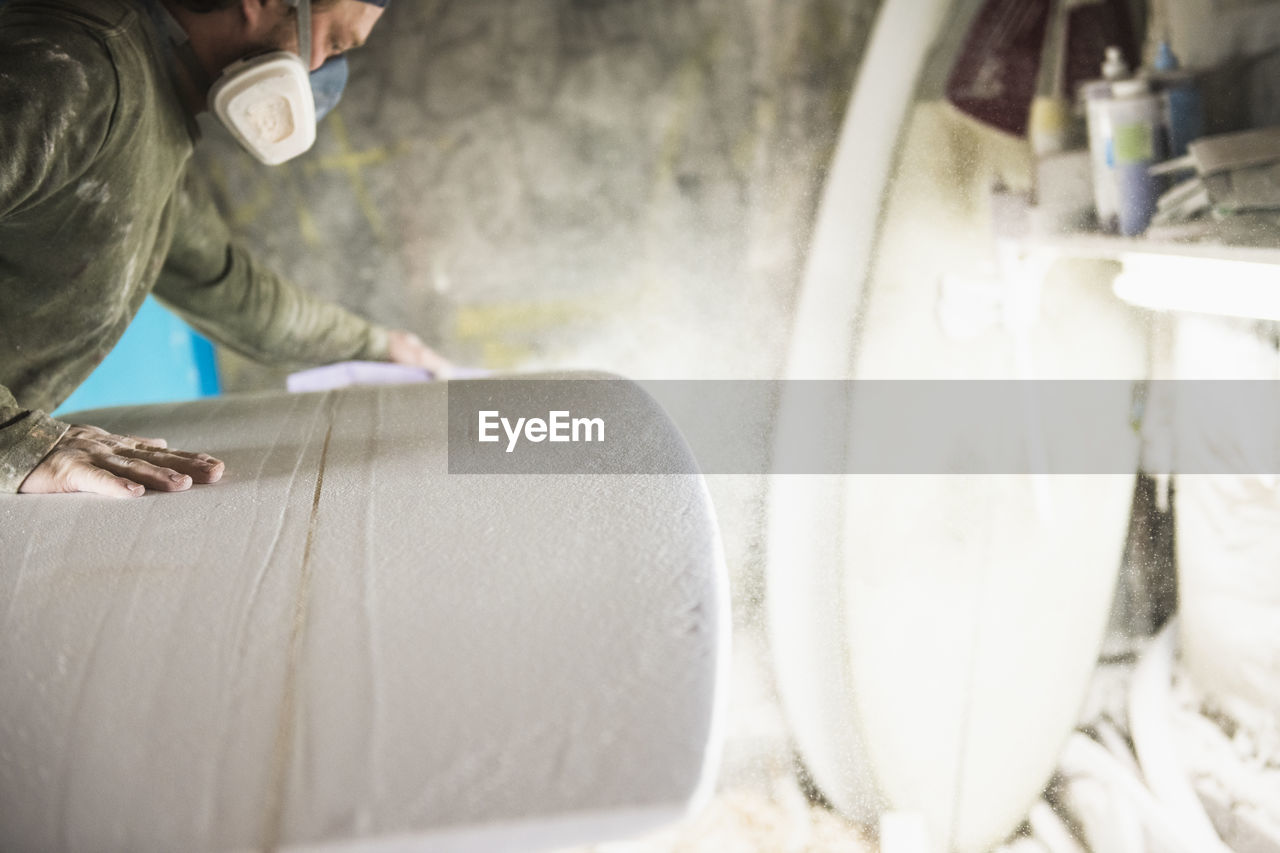 Surfboard shaper sanding a new design