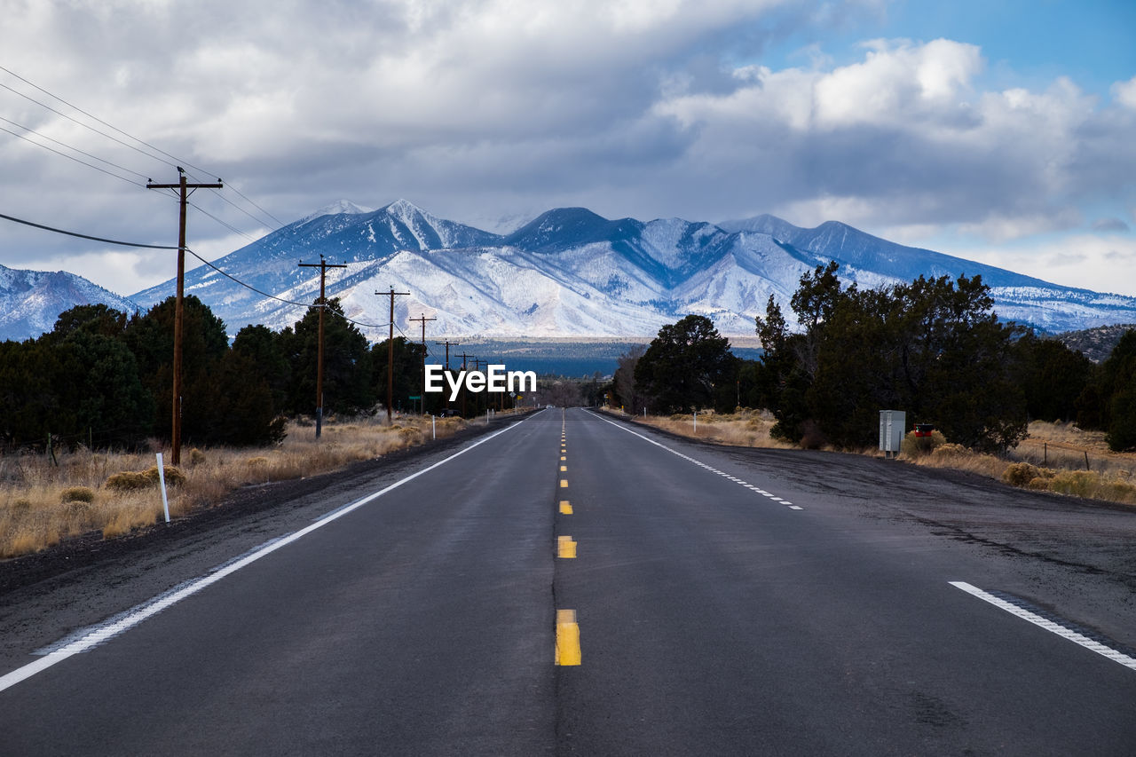 Road leading towards mountains against sky