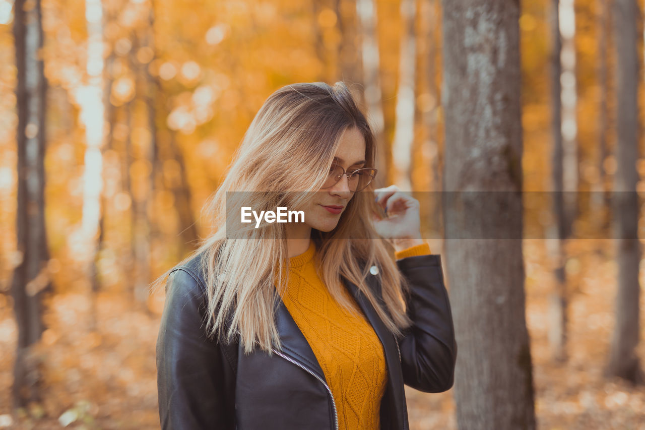 YOUNG WOMAN STANDING IN FOREST