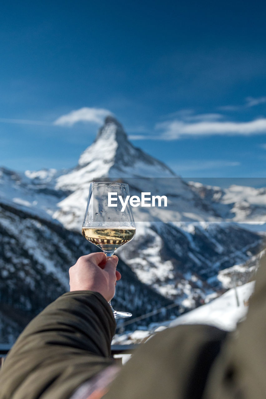 PERSON HOLDING ICE CREAM AGAINST MOUNTAINS