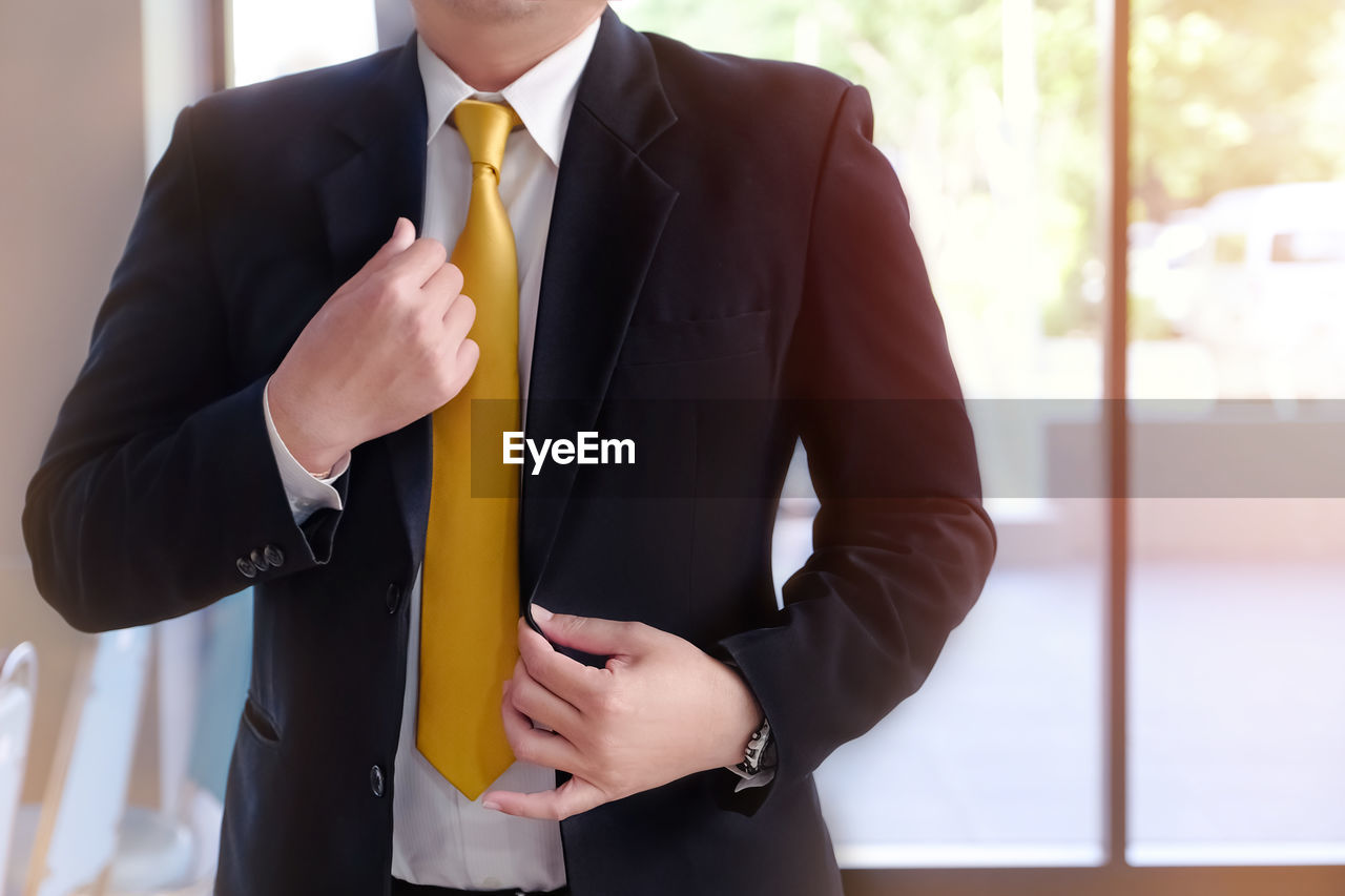Midsection of businessman holding his blazer in office