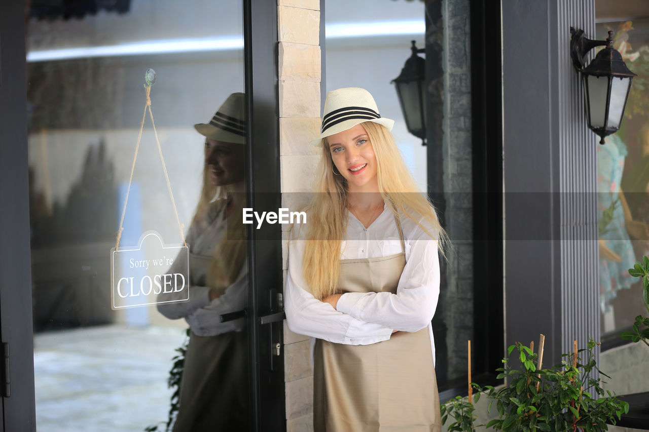 Portrait of smiling young woman standing against door