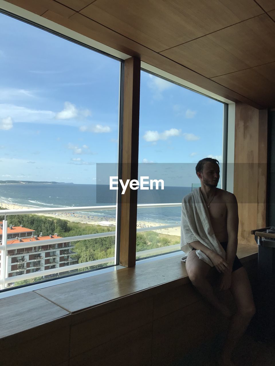 YOUNG WOMAN LOOKING THROUGH WINDOW AT VIEW