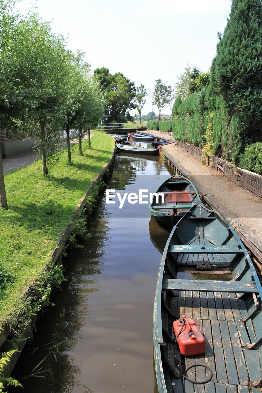 Boats moored in canal against sky