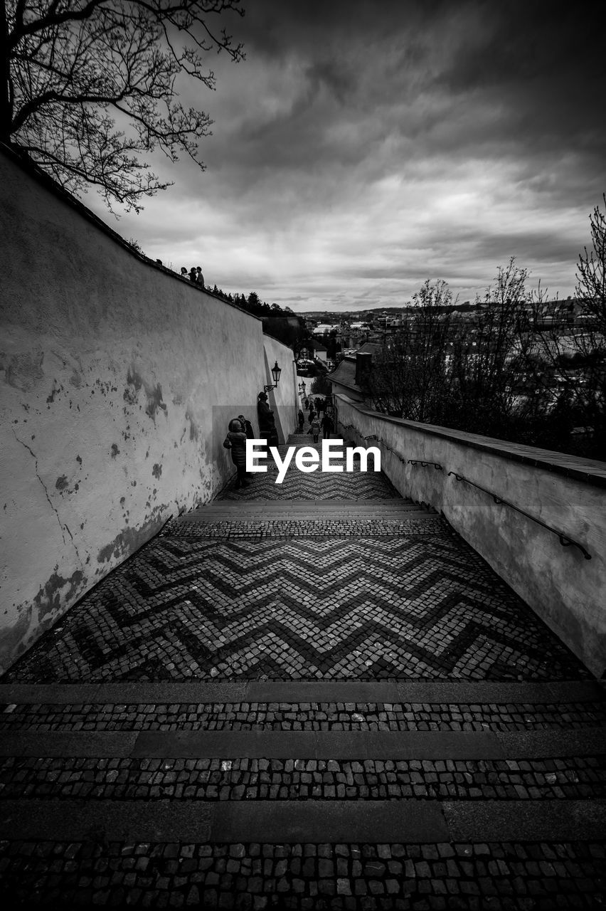 PEOPLE ON FOOTPATH BY SKY AGAINST CLOUDY DAY
