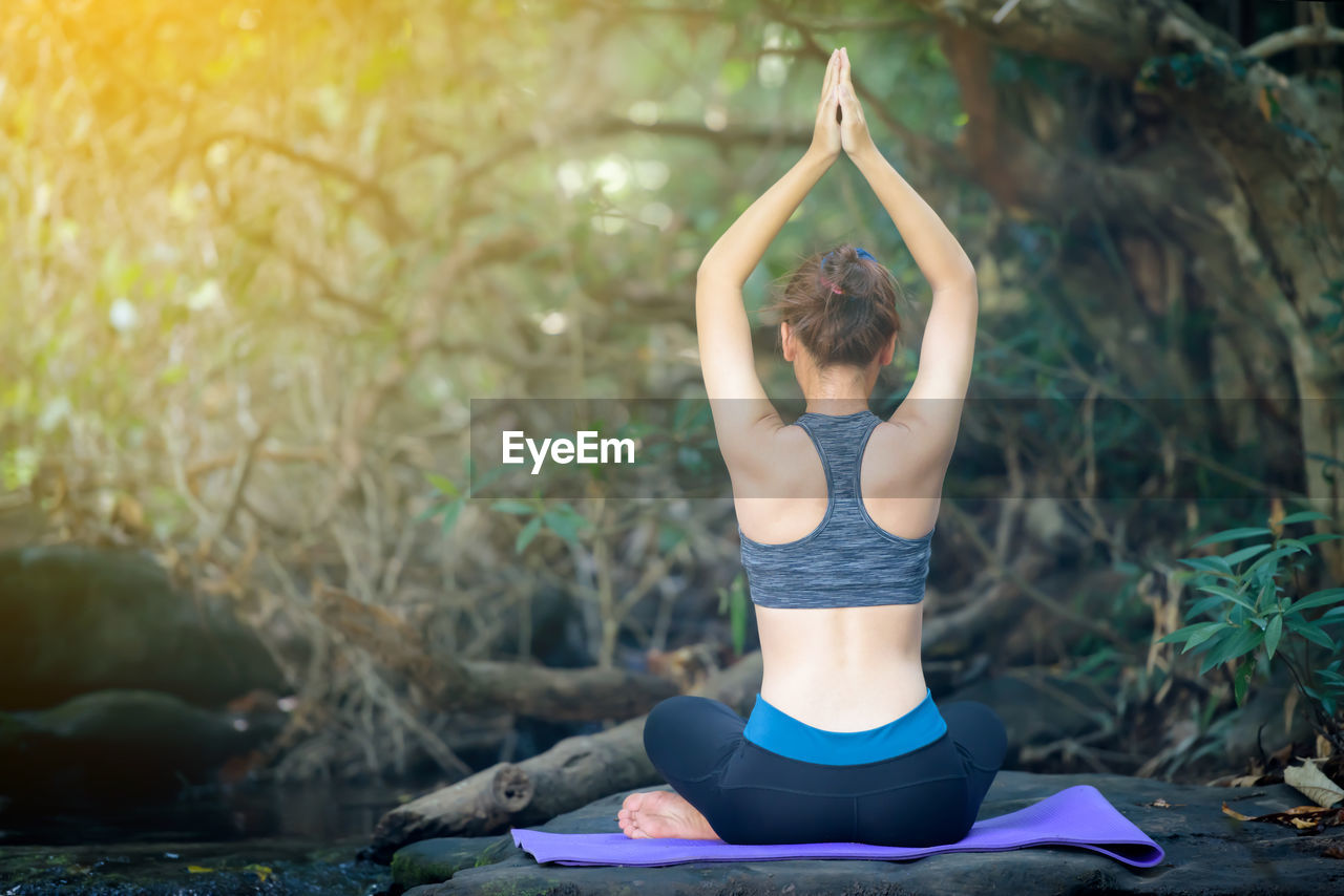 Rear view of teenage girl practicing yoga in forest