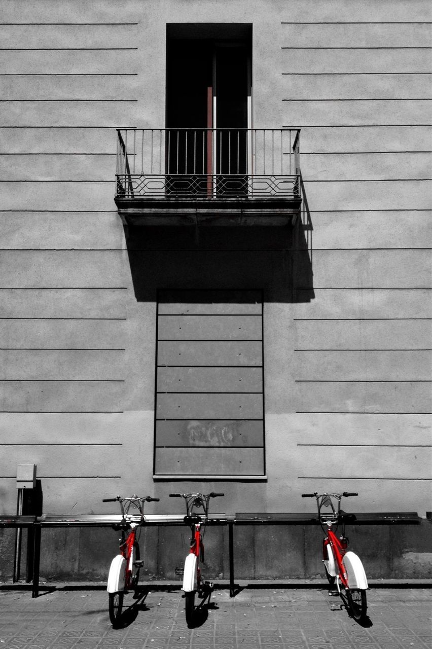 Bicycles parked below balcony and against wall 