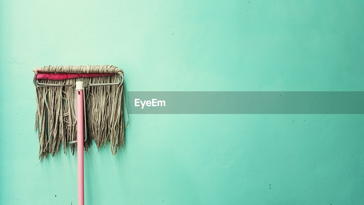 Close-up of mop on green wall
