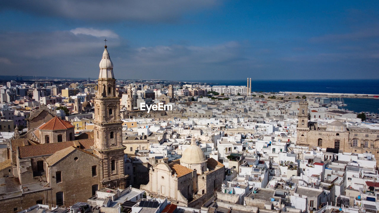 high angle view of buildings by sea against sky