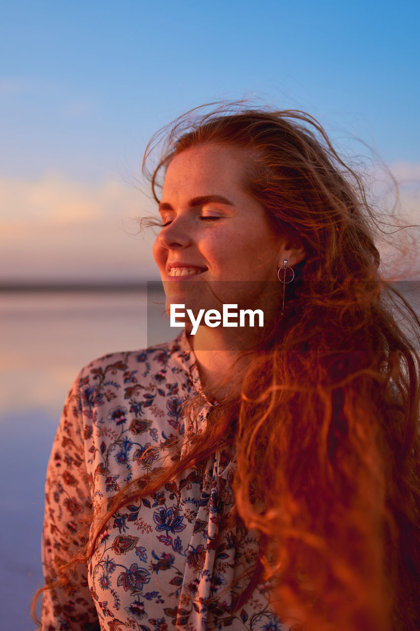 Beautiful smiling young woman with flying red hair person