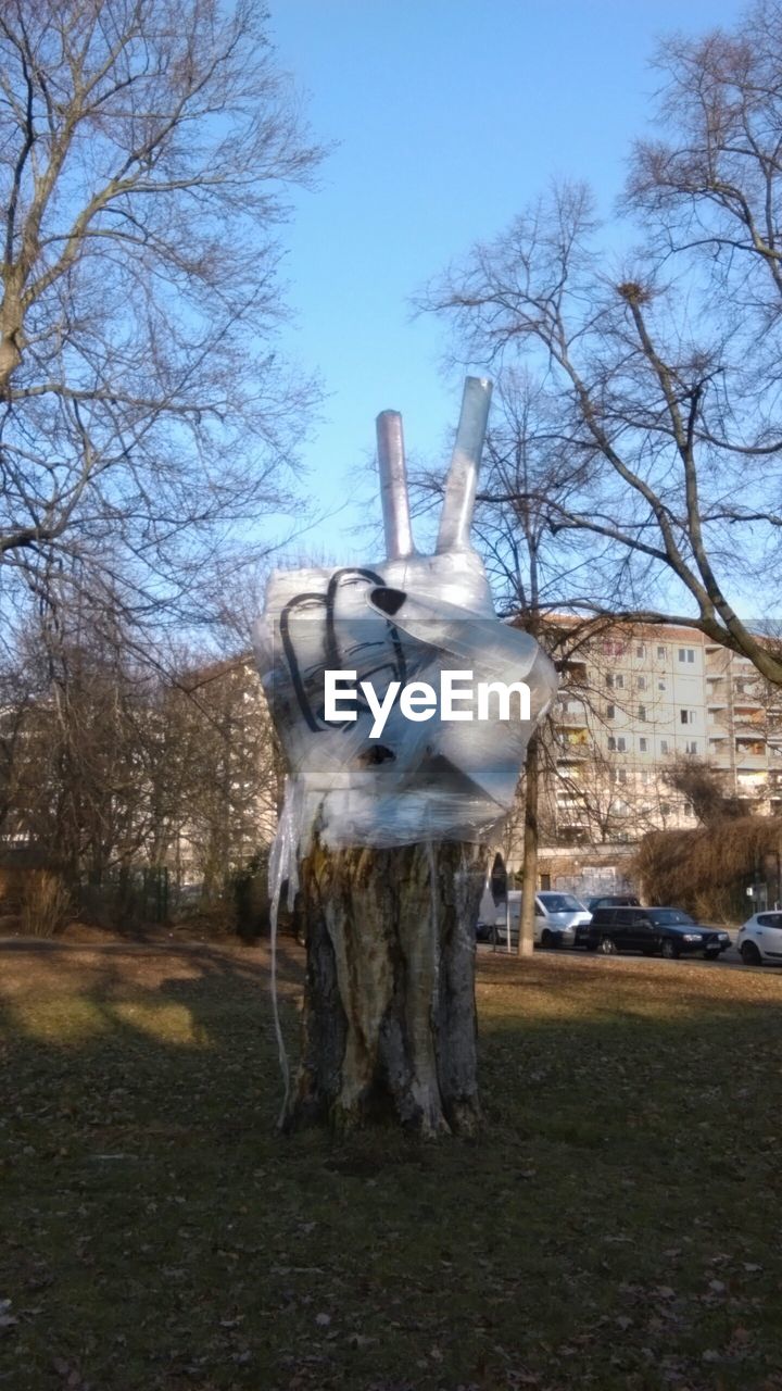 Peace sign made from plastic wrapped on tree against buildings