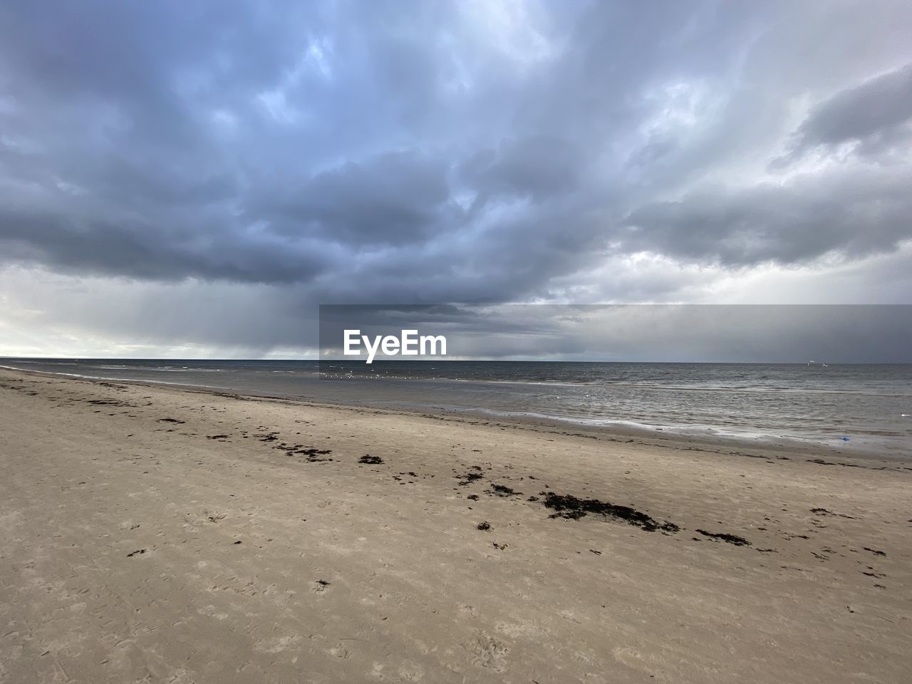 SCENIC VIEW OF BEACH AGAINST CLOUDY SKY