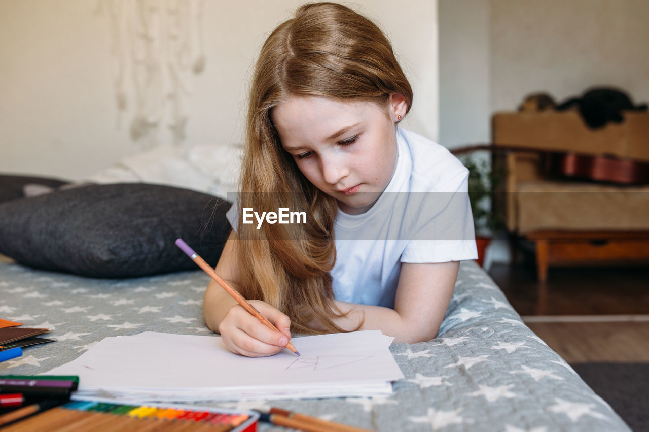 young woman drawing on book at home