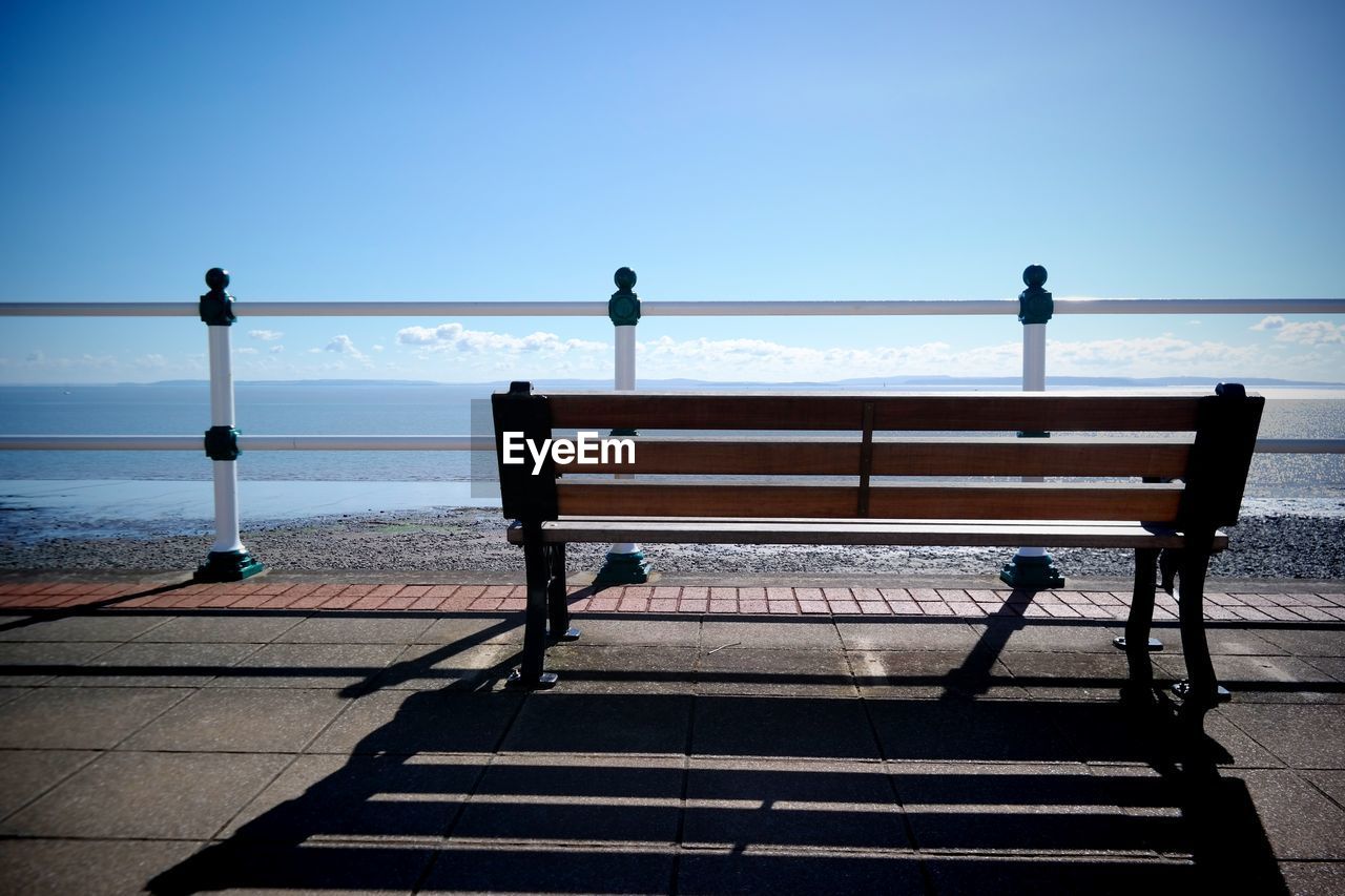 Empty bench at park against clear sky