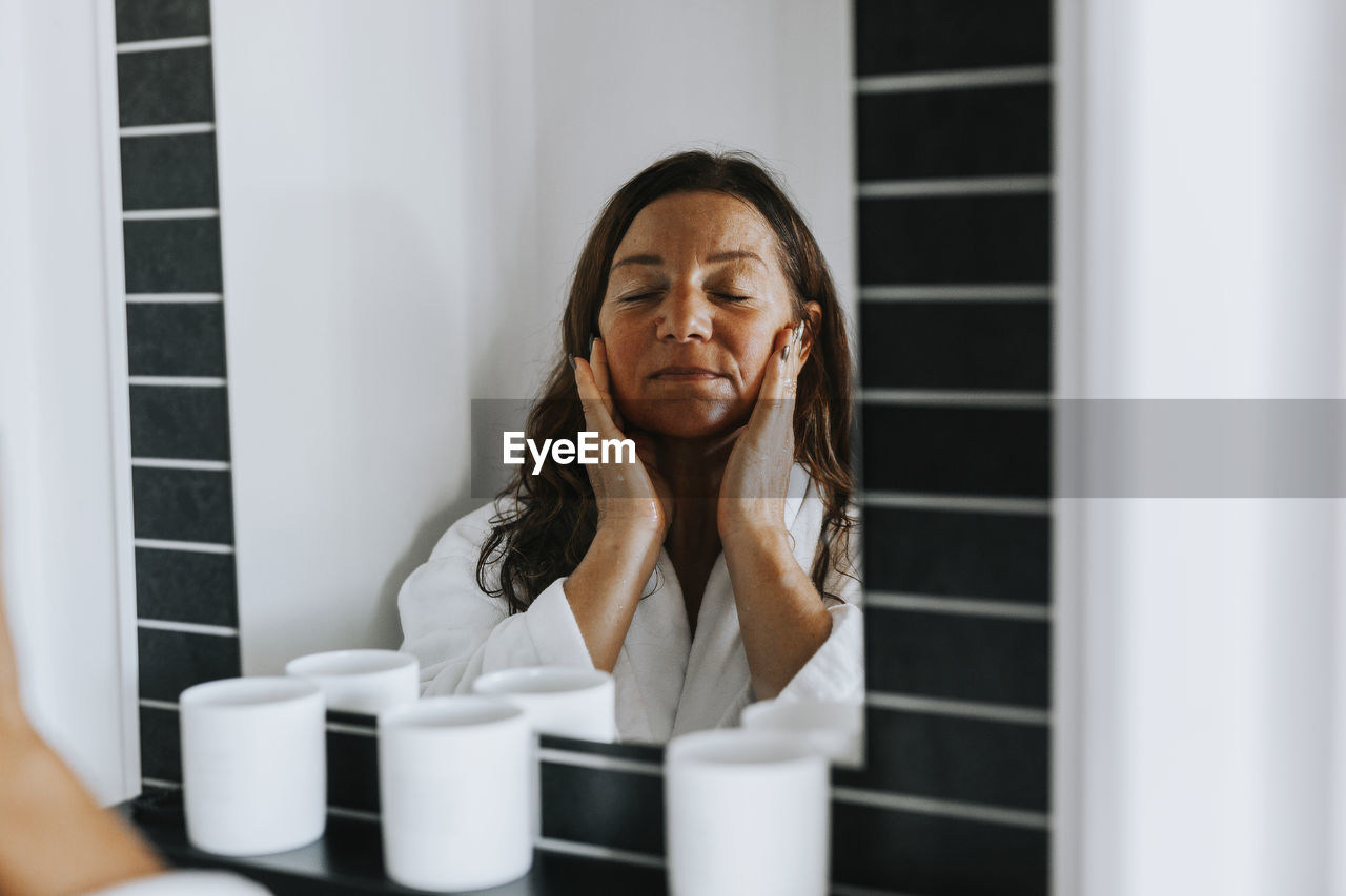 Woman applying moisturizer on her face