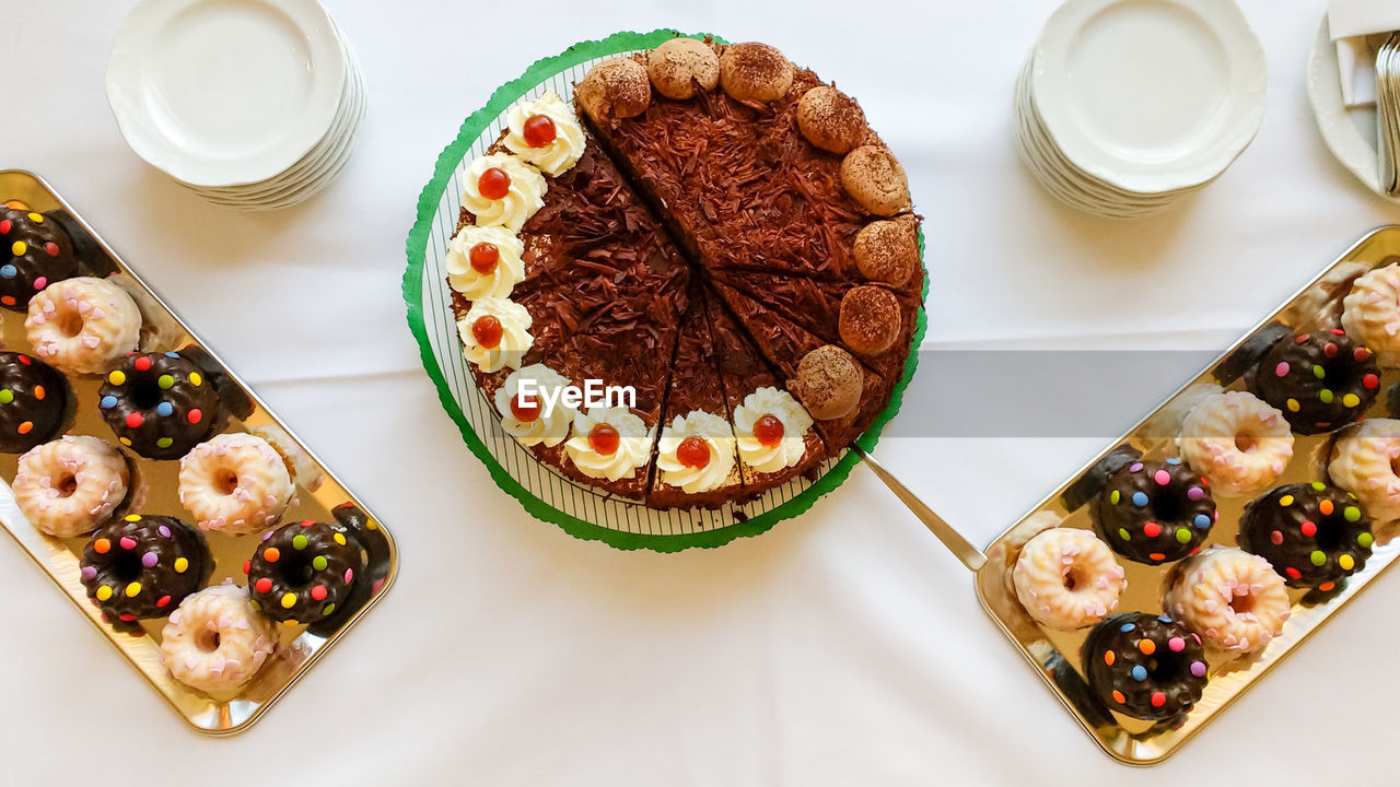 Banquet table with dessert cookies and cake on white tablecloth