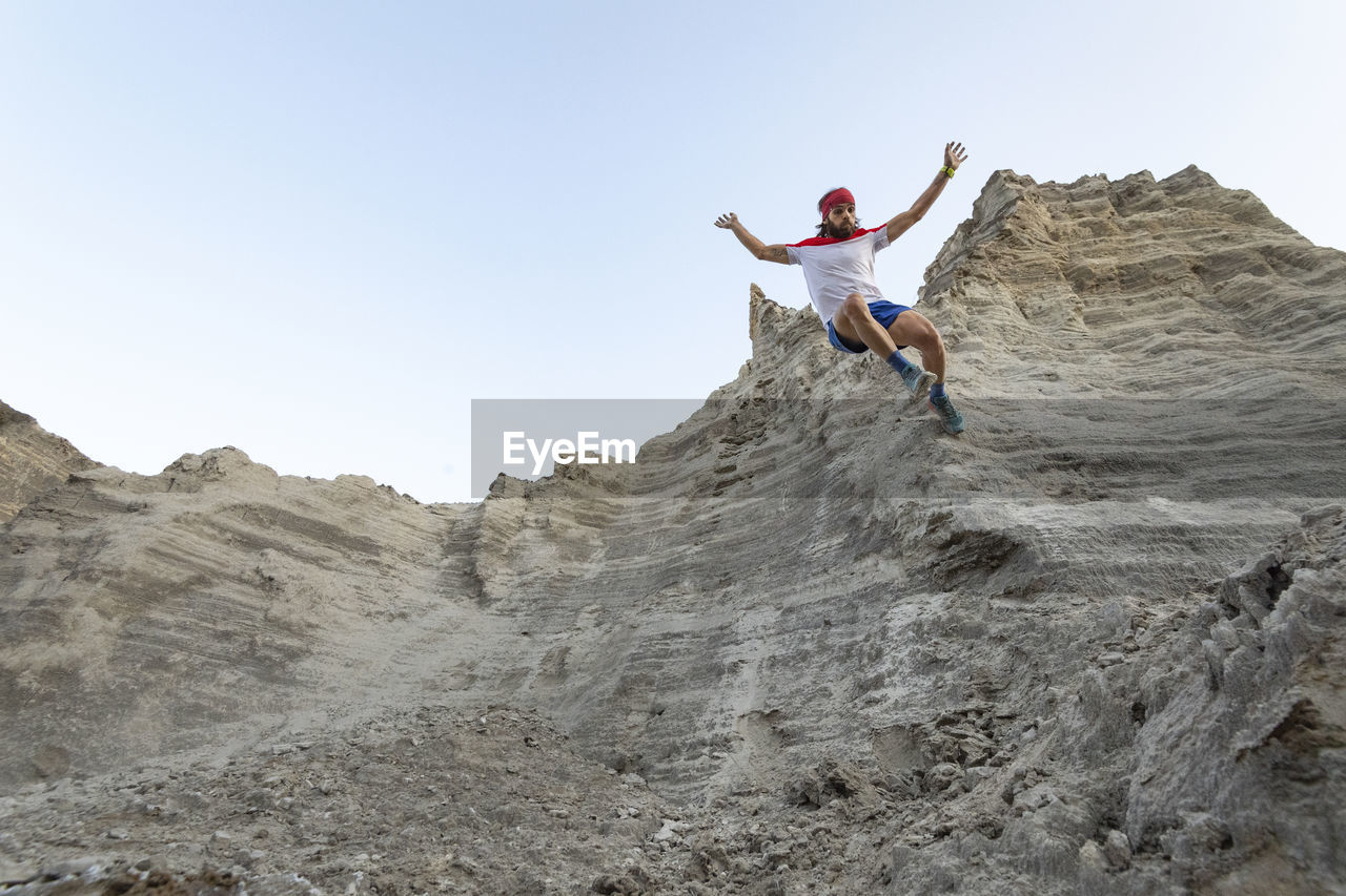 One man runs down on a very steep wall at an old mining waste of sand