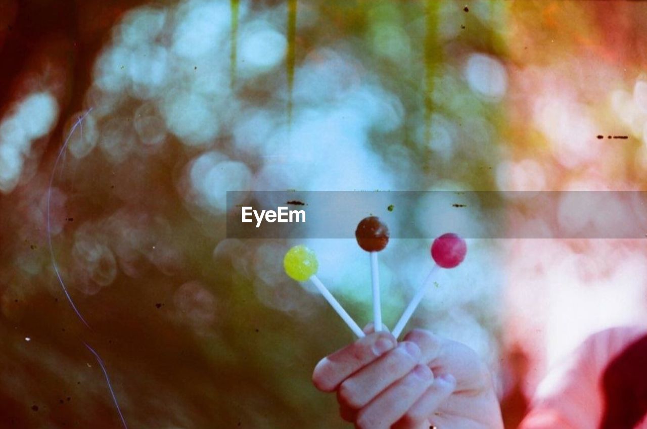 CROPPED IMAGE OF PERSON HOLDING MULTI COLORED UMBRELLA