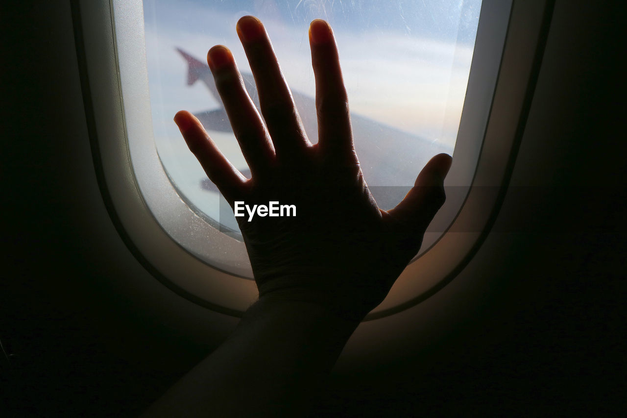 Silhouette of woman's hand against window