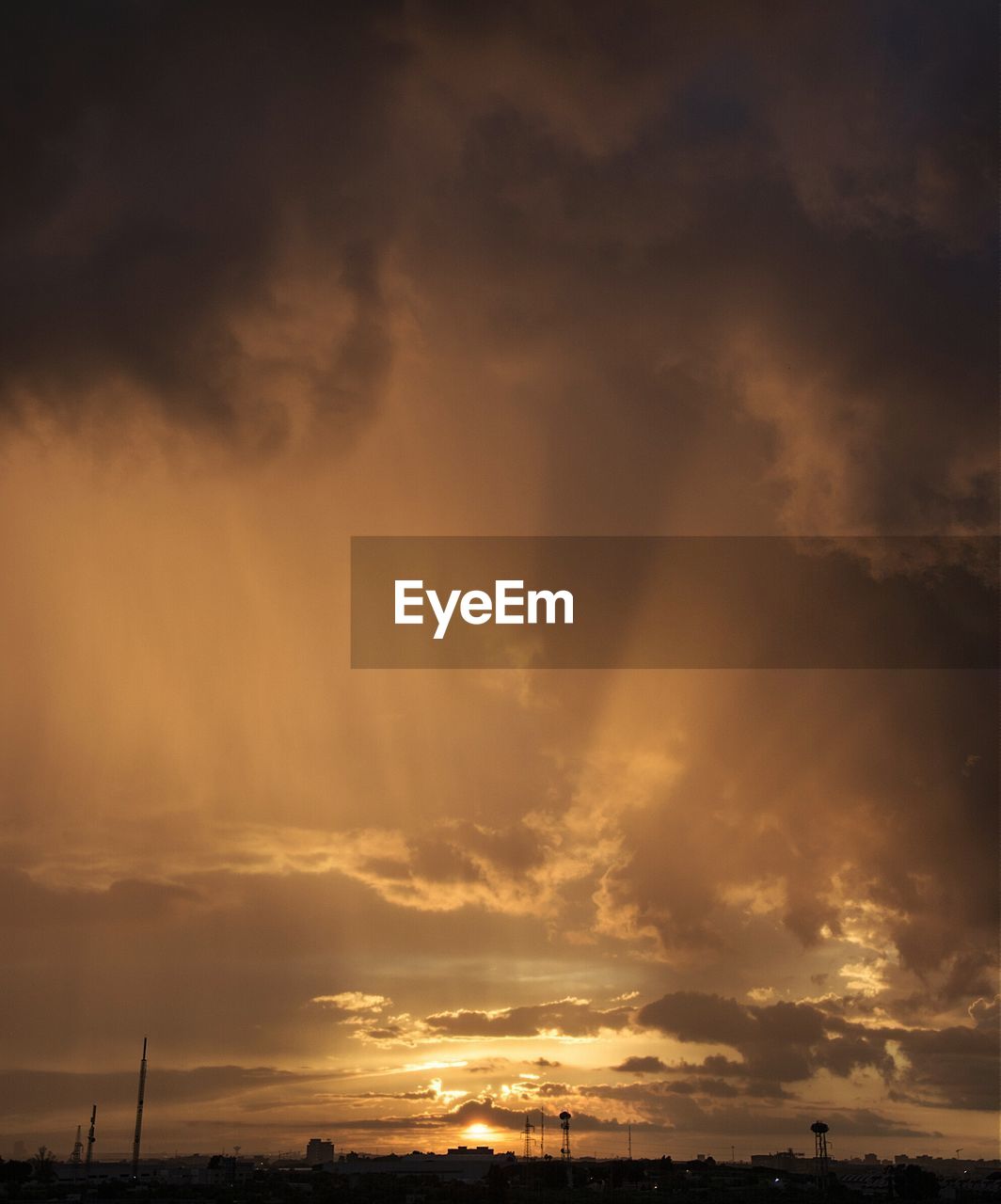 Silhouette of buildings against cloudy sky at dusk