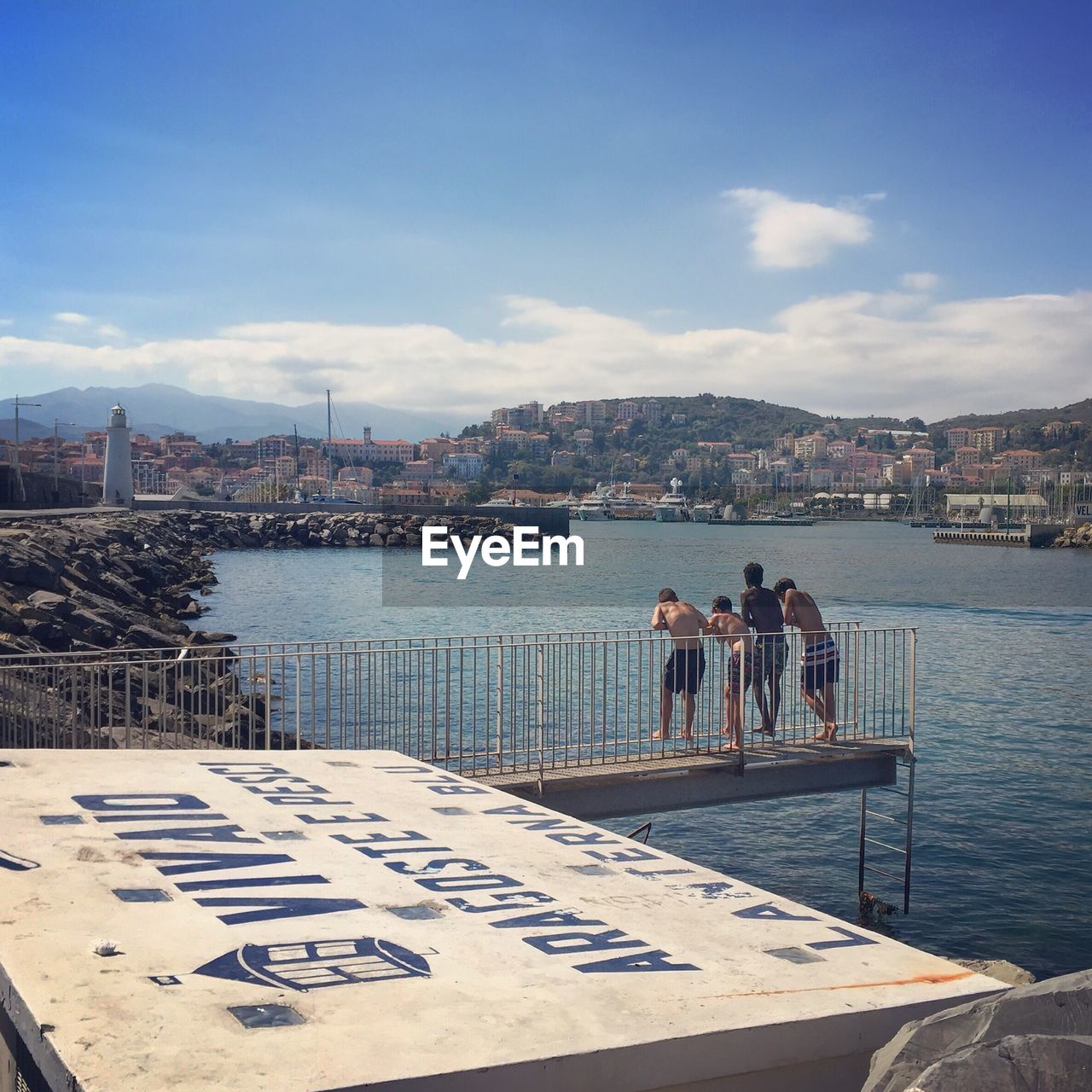 Rear view of friends standing on pier against river
