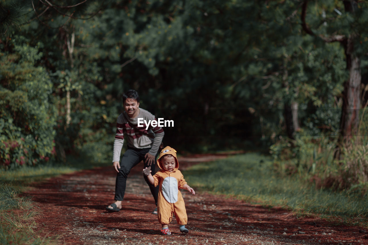 Full length of father and son on tree against plants